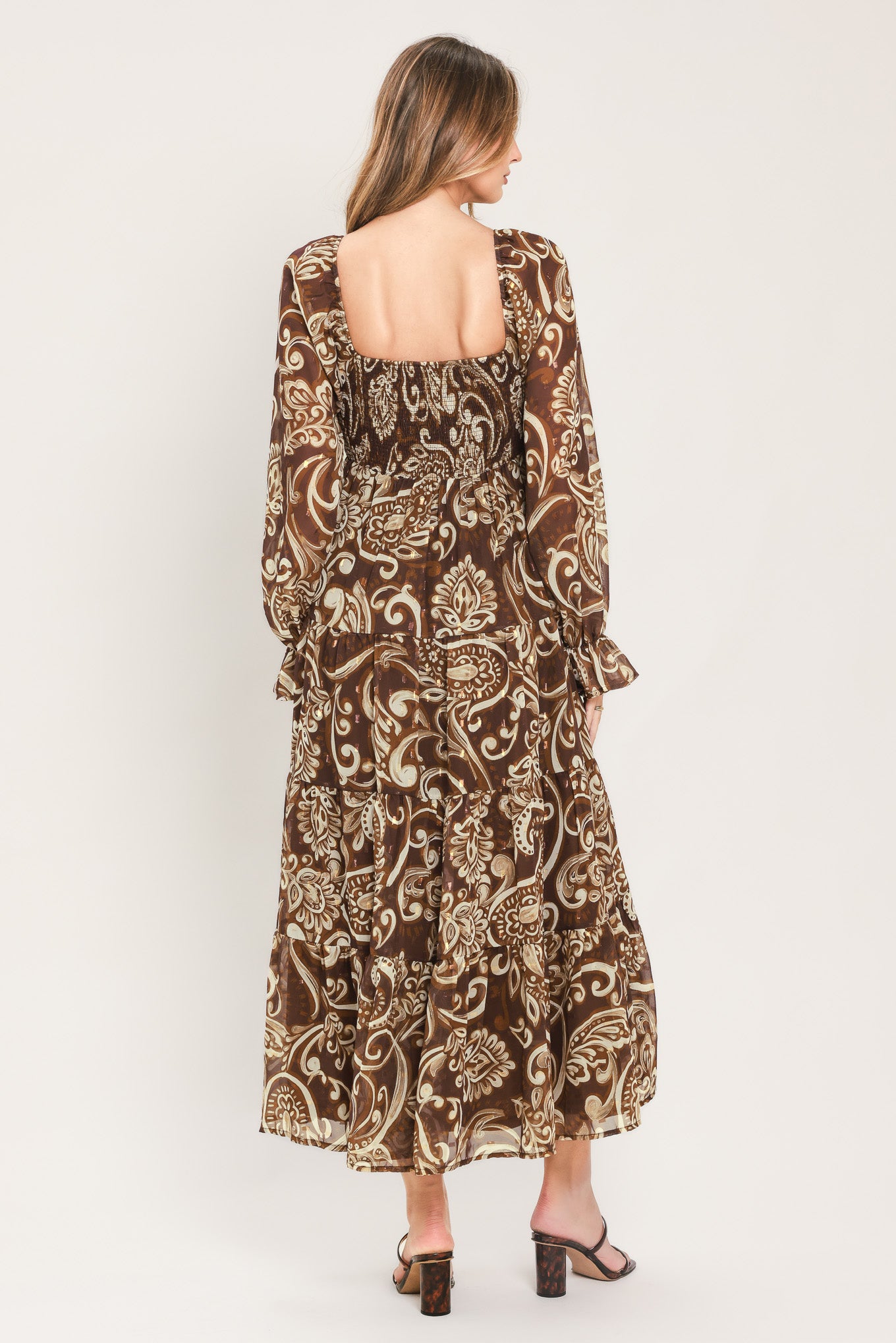 A woman wearing a long-sleeved midi dress with a brown and beige paisley pattern | Flying Tomato