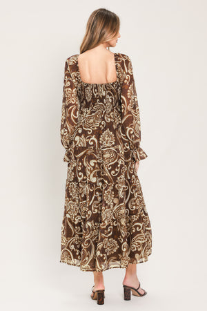 A woman wearing a long-sleeved midi dress with a brown and beige paisley pattern | Flying Tomato
