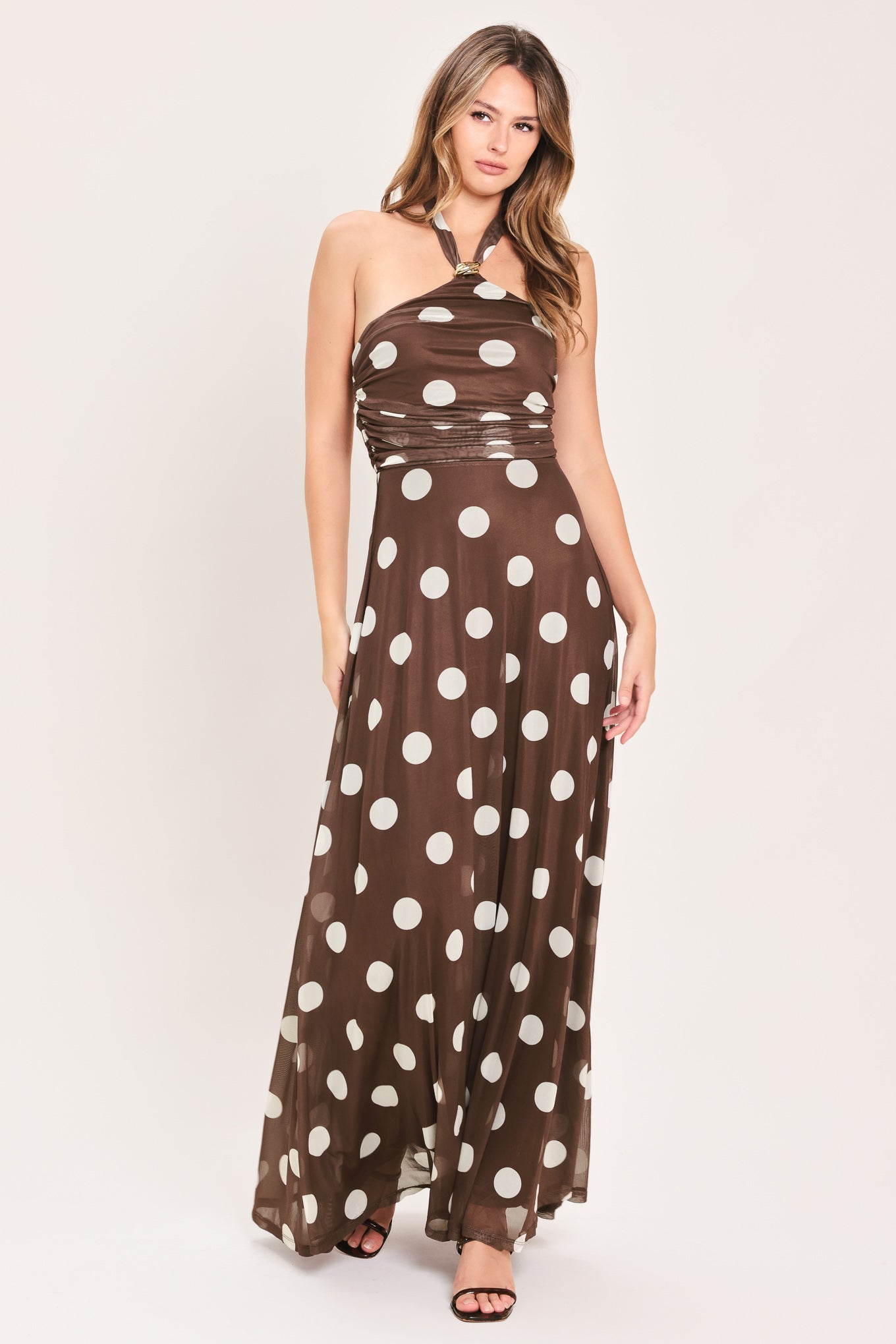 A woman modeling a brown halter-neck maxi dress with a white polka dot pattern | Flying Tomato