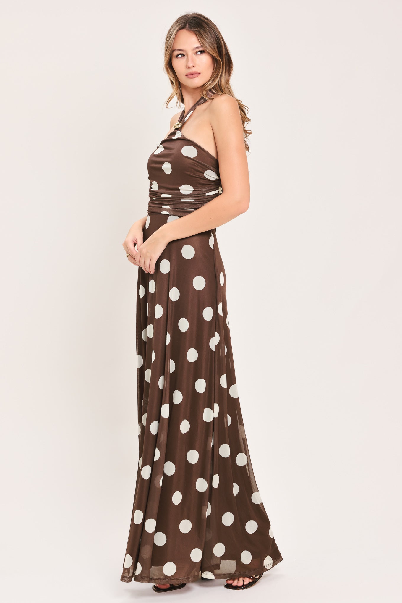 A woman modeling a brown halter-neck maxi dress with a white polka dot pattern | Flying Tomato