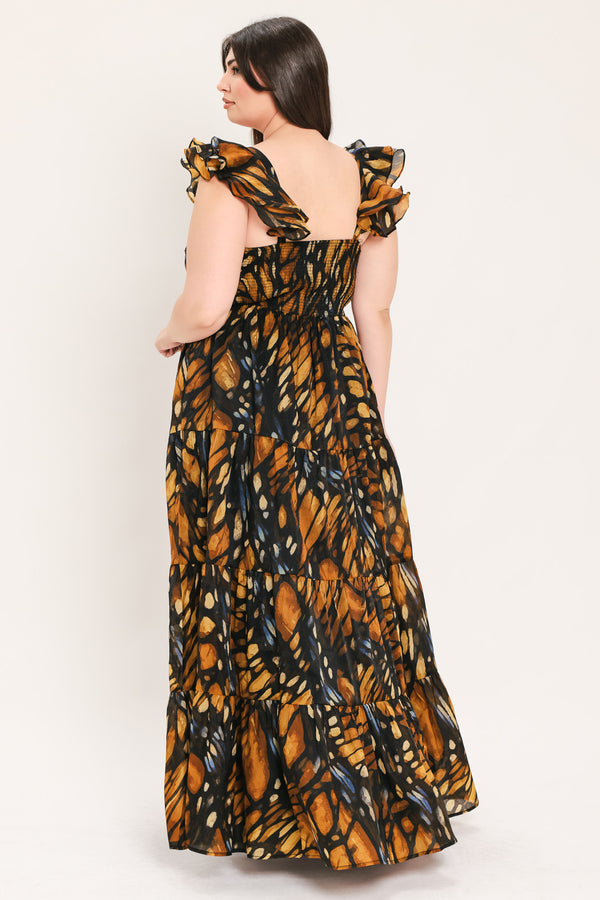 A woman modeling a floor-length tiered maxi dress with a black and orange butterfly wing print, featuring ruffled shoulder straps and a sweetheart neckline, set against a plain light gray studio background | Flying Tomato Curve