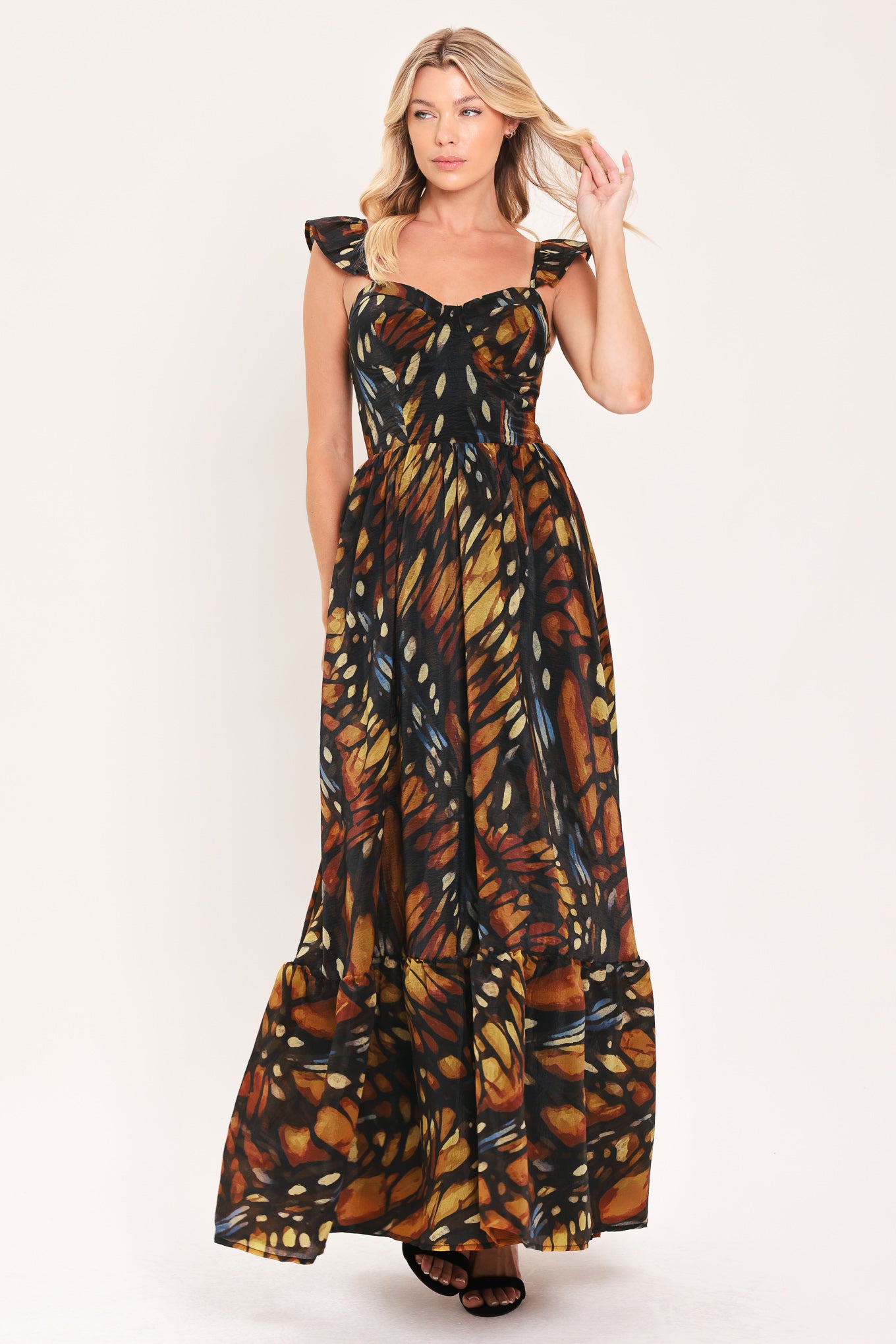 A woman modeling a maxi sleeveless dress with a butterfly wing print in orange, brown, black, and beige tones | Flying Tomato