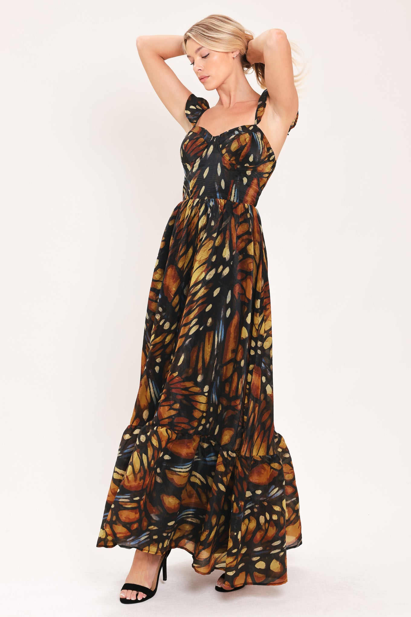 A woman modeling a maxi sleeveless dress with a butterfly wing print in orange, brown, black, and beige tones | Flying Tomato