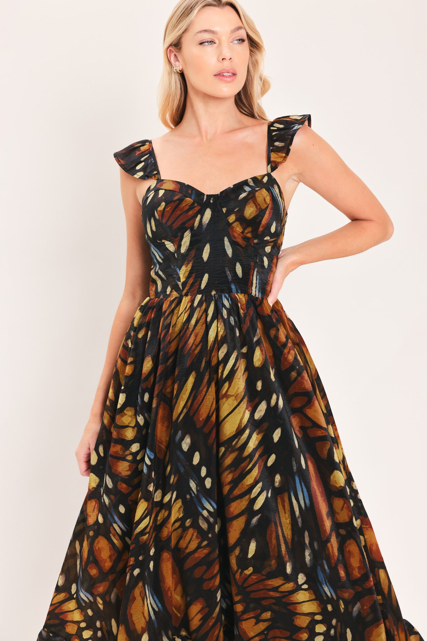 A woman modeling a maxi sleeveless dress with a butterfly wing print in orange, brown, black, and beige tones | Flying Tomato