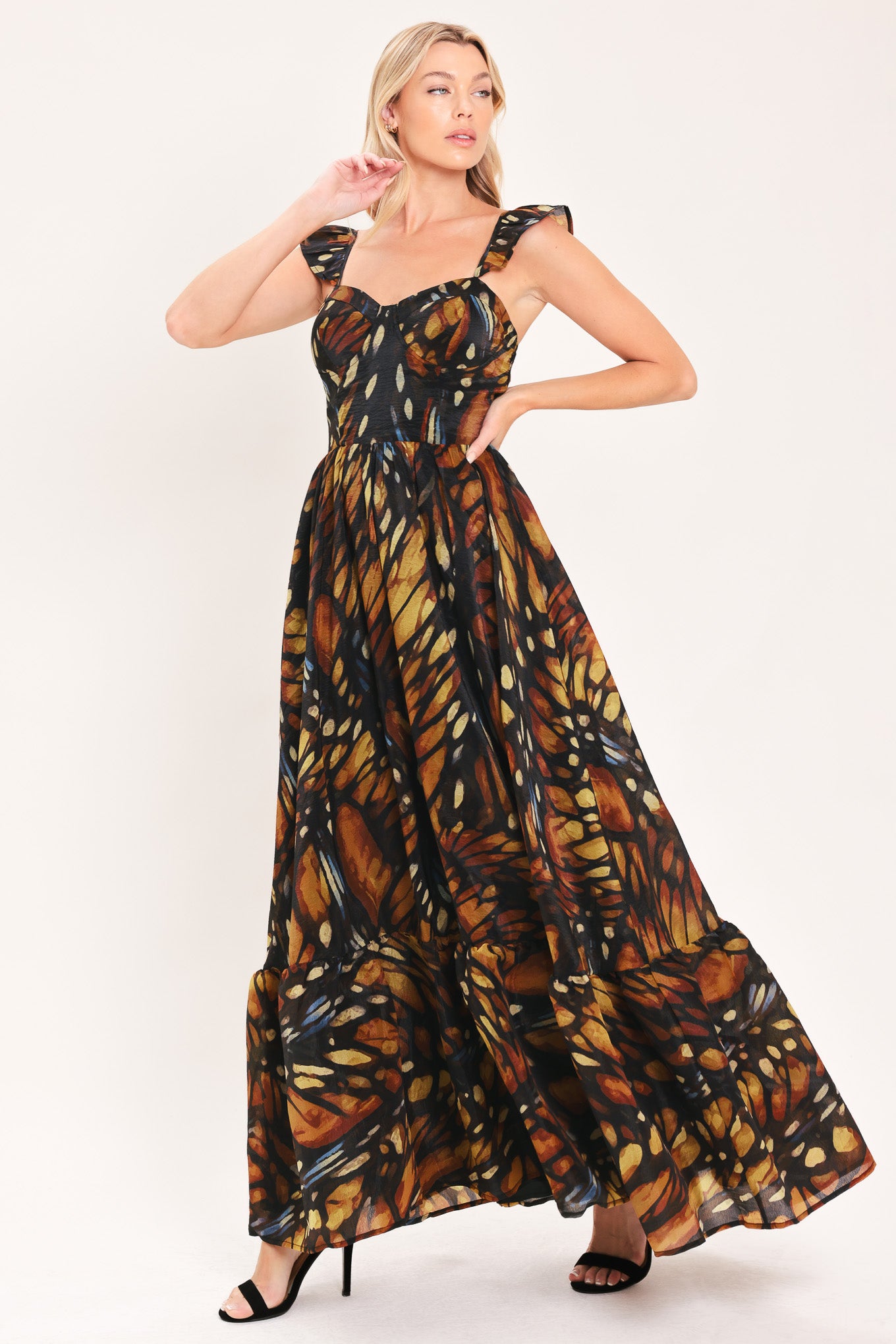 A woman modeling a maxi sleeveless dress with a butterfly wing print in orange, brown, black, and beige tones | Flying Tomato