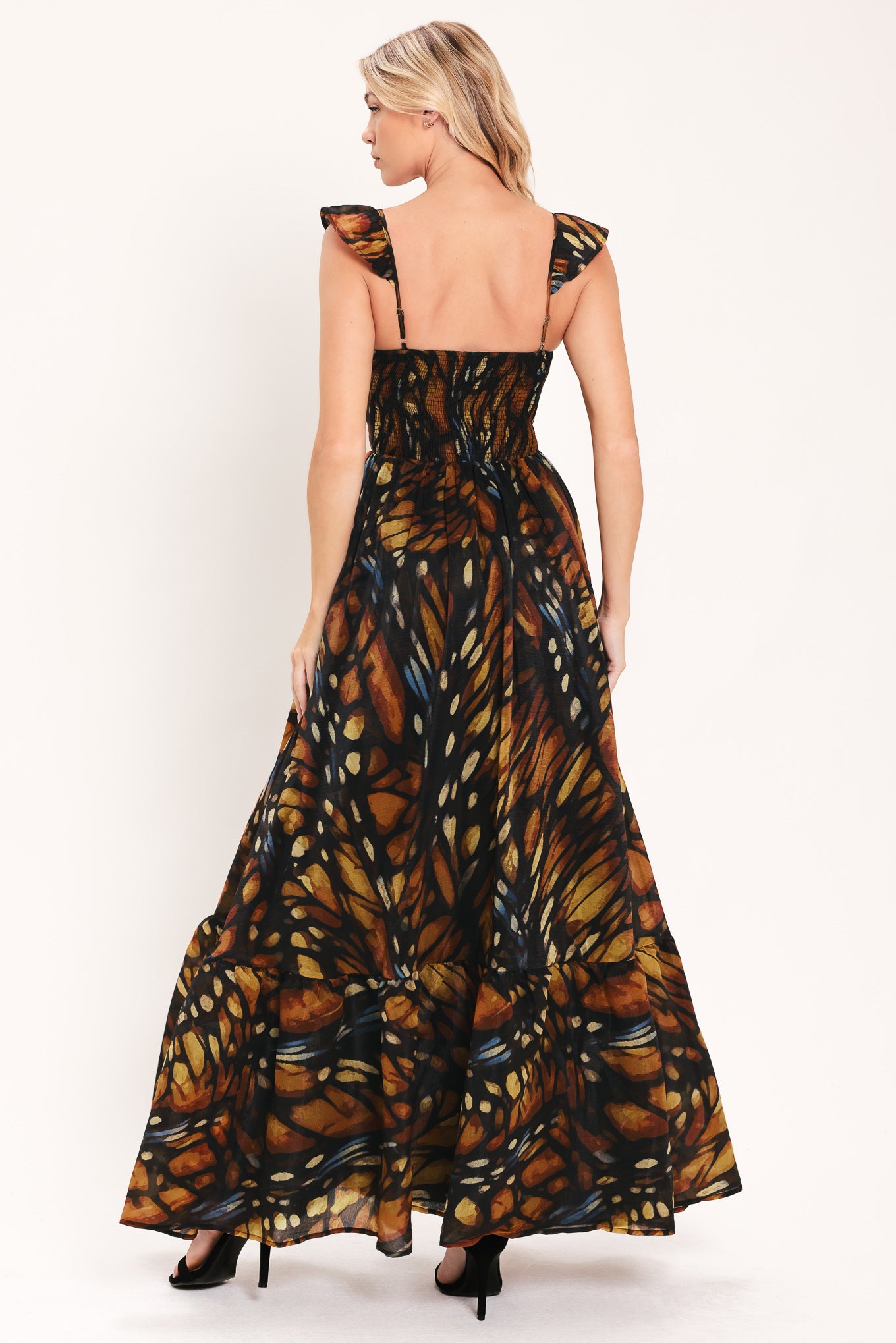A woman modeling a maxi sleeveless dress with a butterfly wing print in orange, brown, black, and beige tones | Flying Tomato