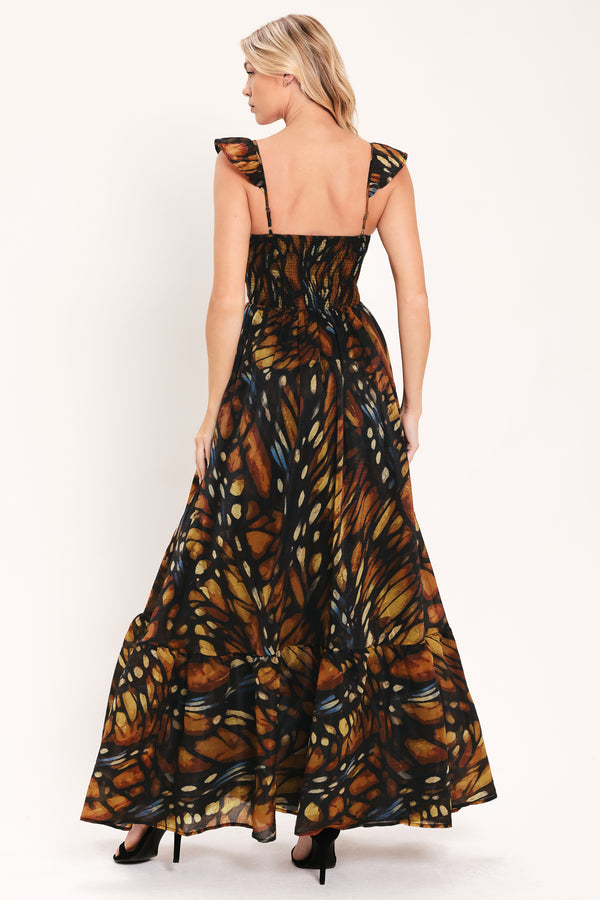 A woman modeling a maxi sleeveless dress with a butterfly wing print in orange, brown, black, and beige tones | Flying Tomato