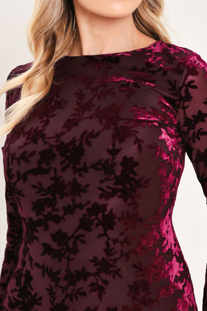 A woman modeling a long-sleeve, midi-length burgundy velvet dress with a tonal floral jacquard pattern | Flying Tomato