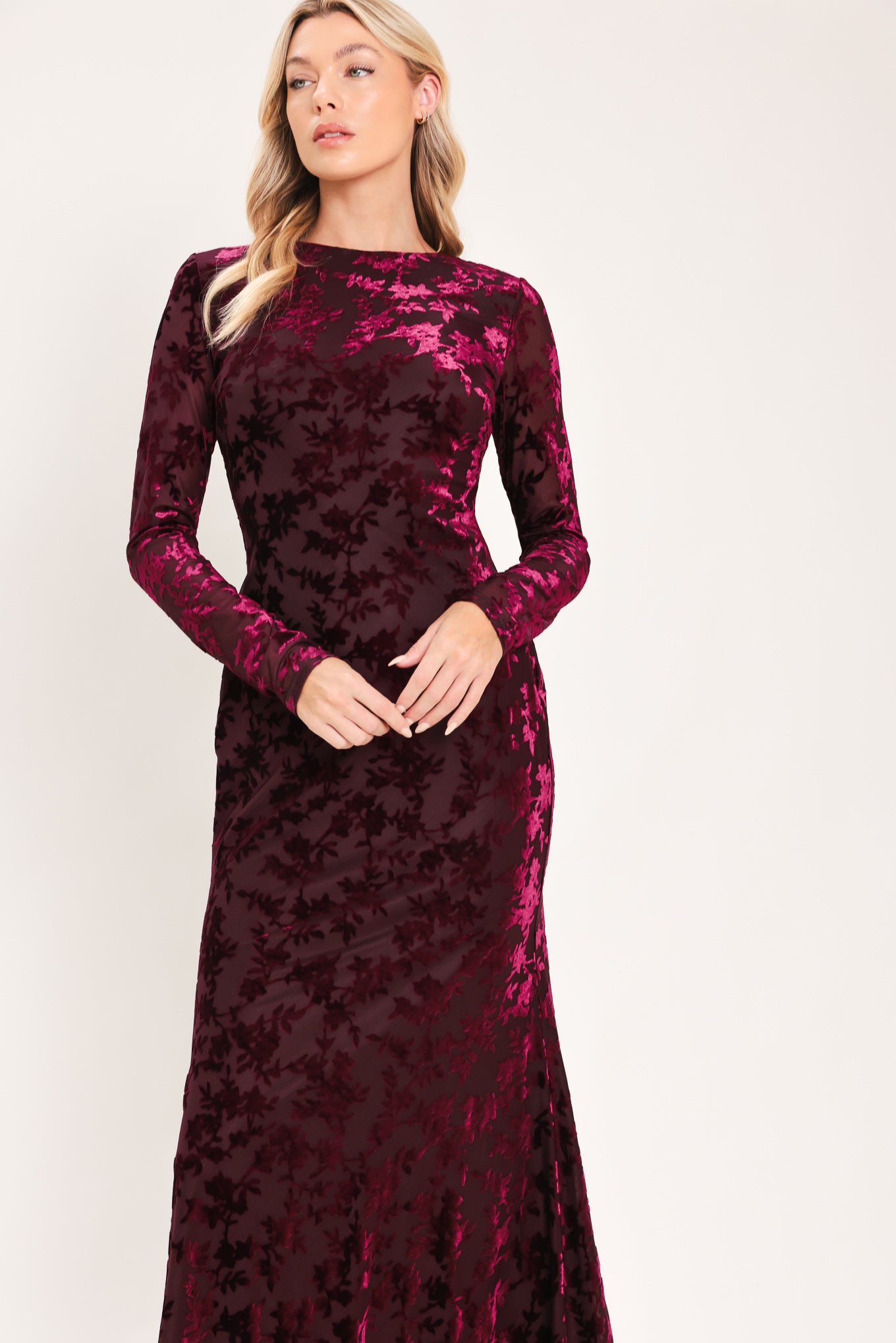 A woman modeling a long-sleeve, midi burgundy velvet dress with an allover tonal floral jacquard pattern | Flying Tomato