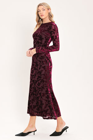 A woman modeling a long-sleeve, midi burgundy velvet dress with an allover tonal floral jacquard pattern | Flying Tomato