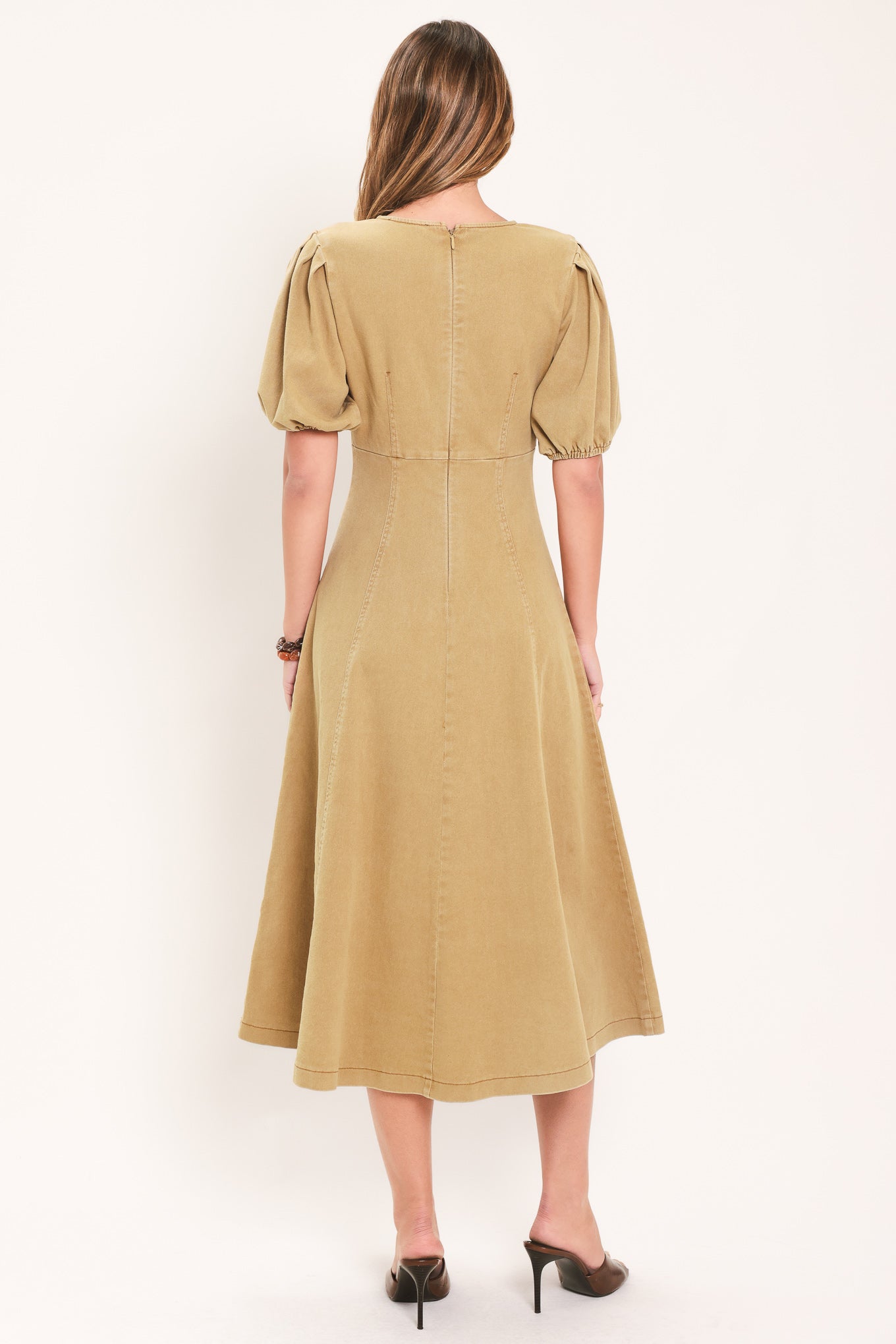 A woman modeling a tan midi dress with puff sleeves, a round neckline, and a flared skirt | Flying Tomato