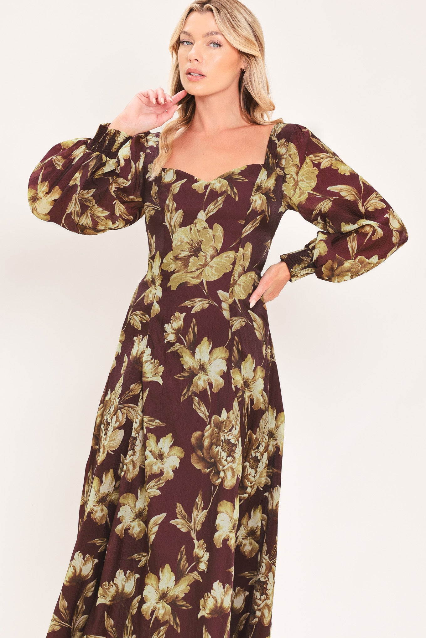 A woman modeling a long-sleeved midi dress with a burgundy and olive green floral pattern | Flying Tomato