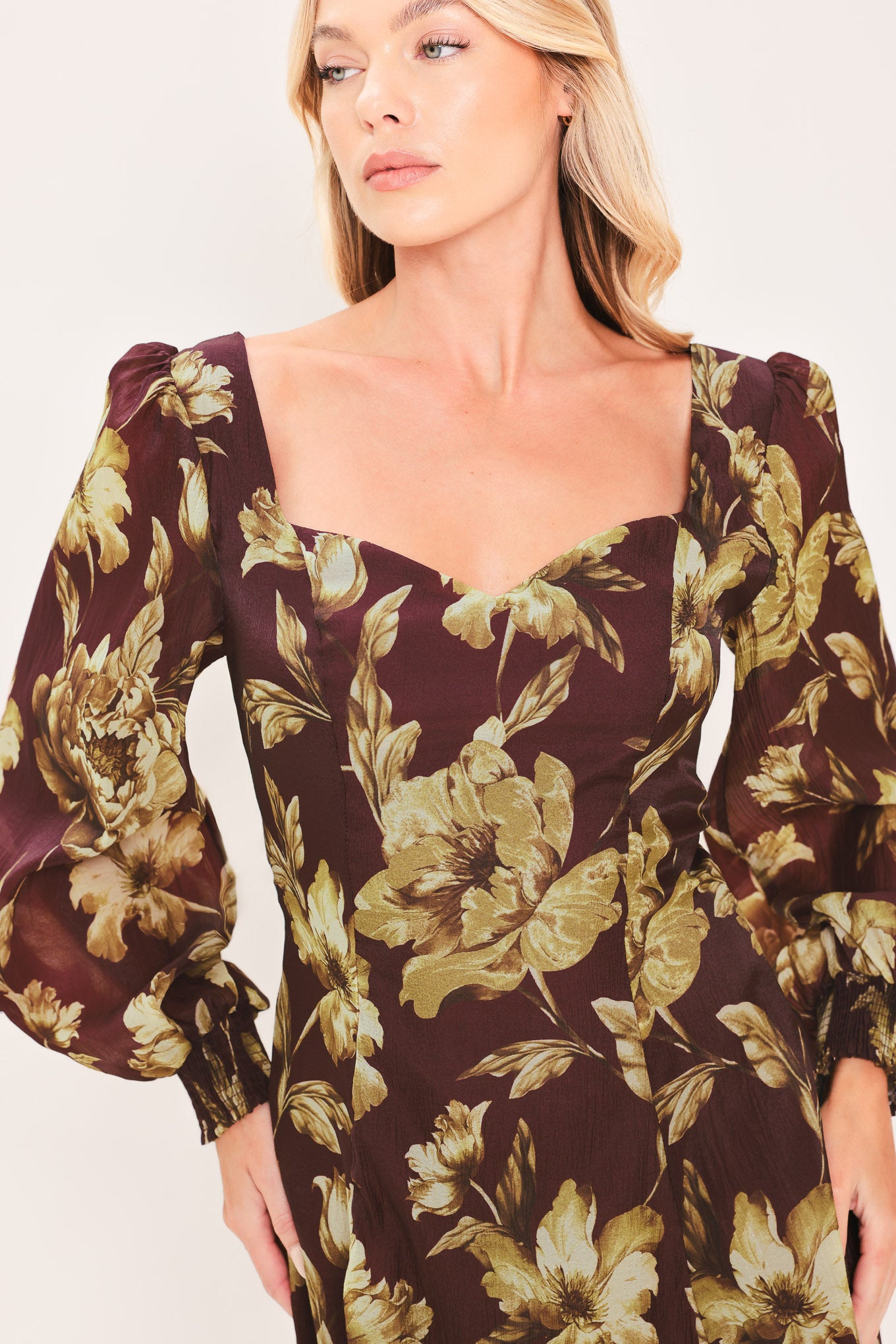 A woman modeling a long-sleeved midi dress with a burgundy and olive green floral pattern | Flying Tomato