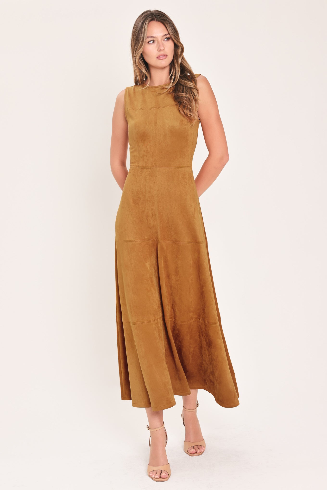 A woman modeling a sleeveless, high-neck, midi-length camel brown dress with a flared skirt | Flying Tomato