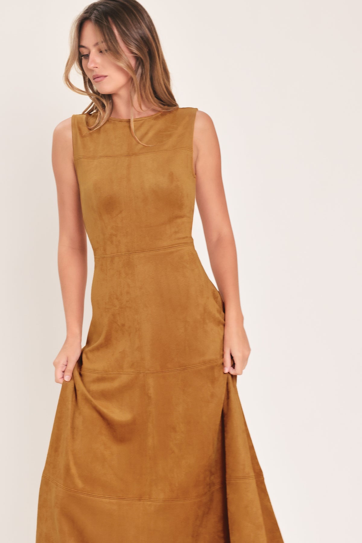 A woman modeling a sleeveless, high-neck, midi-length camel brown dress with a flared skirt | Flying Tomato