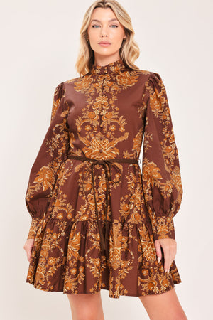 A woman modeling a brown and gold damask-patterned long-sleeve mini dress with a high mock neck and a matching waist tie | Flying Tomato