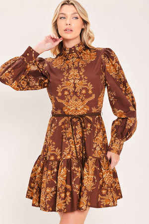 A woman modeling a brown and gold damask-patterned long-sleeve mini dress with a high mock neck and a matching waist tie | Flying Tomato