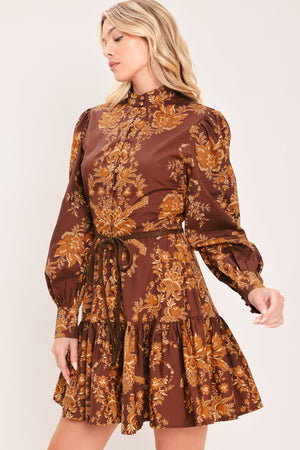 A woman modeling a brown and gold damask-patterned long-sleeve mini dress with a high mock neck and a matching waist tie | Flying Tomato