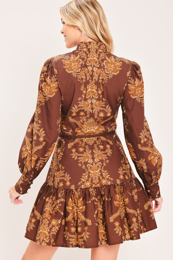 A woman modeling a brown and gold damask-patterned long-sleeve mini dress with a high mock neck and a matching waist tie | Flying Tomato