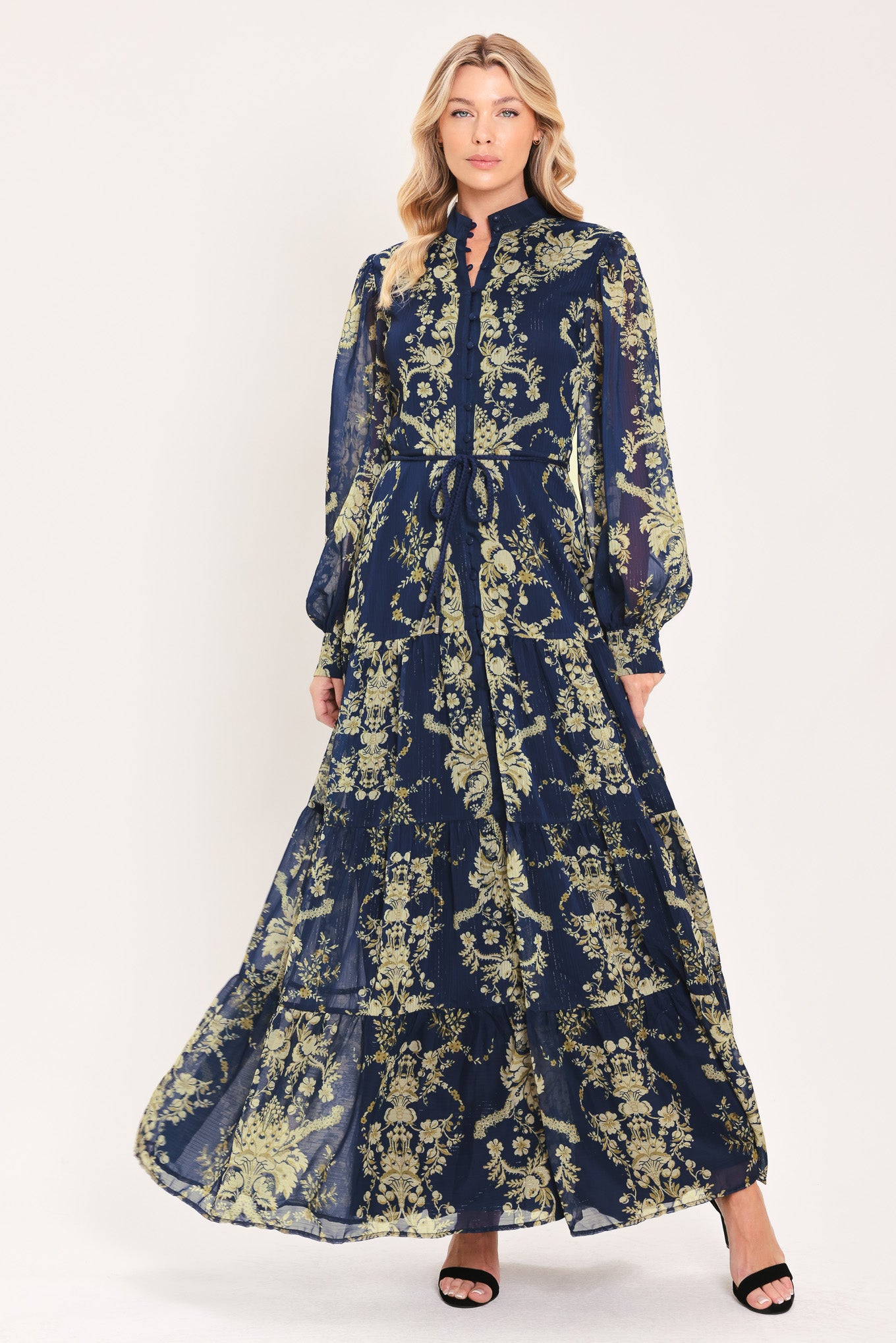 A woman modeling a long-sleeved navy blue maxi dress with a taupe toile floral pattern | Flying Tomato