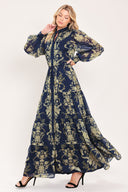 A woman modeling a long-sleeved navy blue maxi dress with a taupe toile floral pattern | Flying Tomato