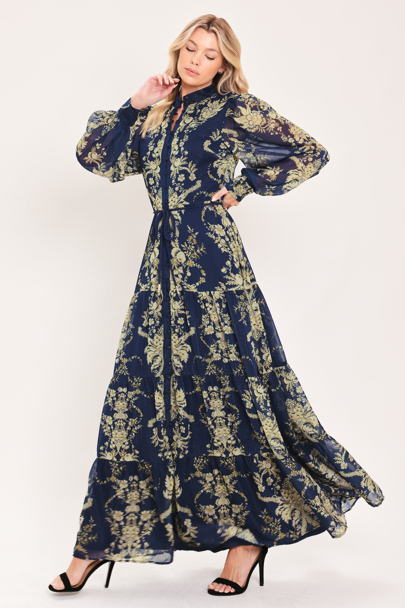 A woman modeling a long-sleeved navy blue maxi dress with a taupe toile floral pattern | Flying Tomato
