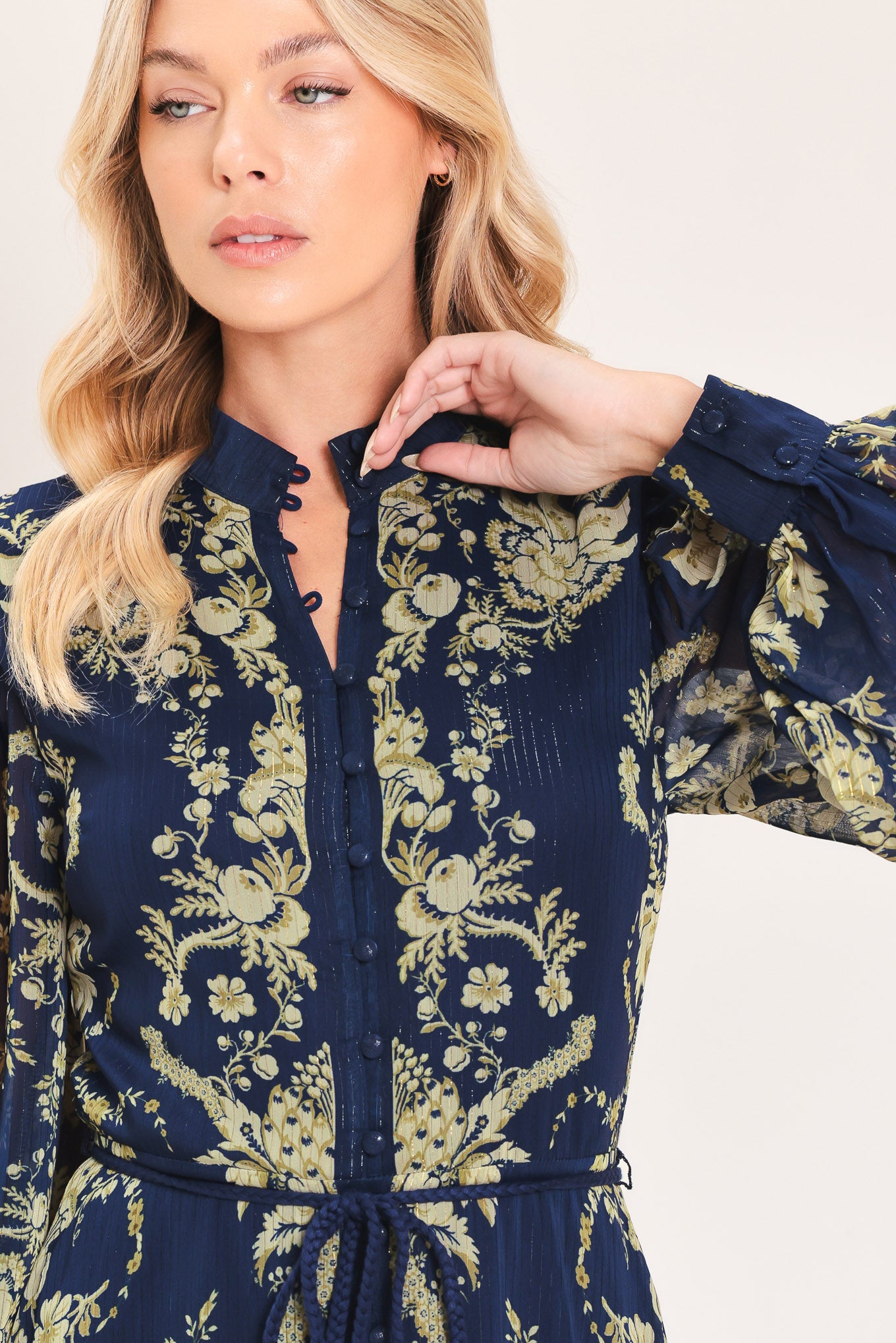 A woman modeling a long-sleeved navy blue maxi dress with a taupe toile floral pattern | Flying Tomato