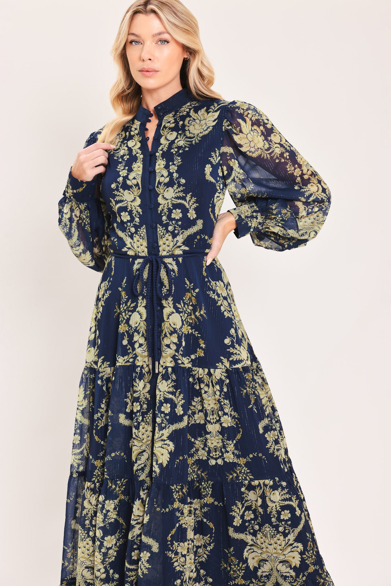 A woman modeling a long-sleeved navy blue maxi dress with a taupe toile floral pattern | Flying Tomato