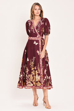 A woman wearing a burgundy midi wrap dress with a floral and butterfly print, featuring puff sleeves, a V-neckline, and a matching waist tie | Flying Tomato