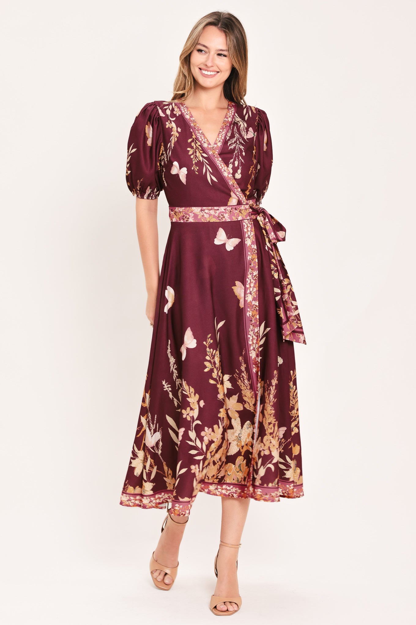 A woman wearing a burgundy midi wrap dress with a floral and butterfly print, featuring puff sleeves, a V-neckline, and a matching waist tie | Flying Tomato