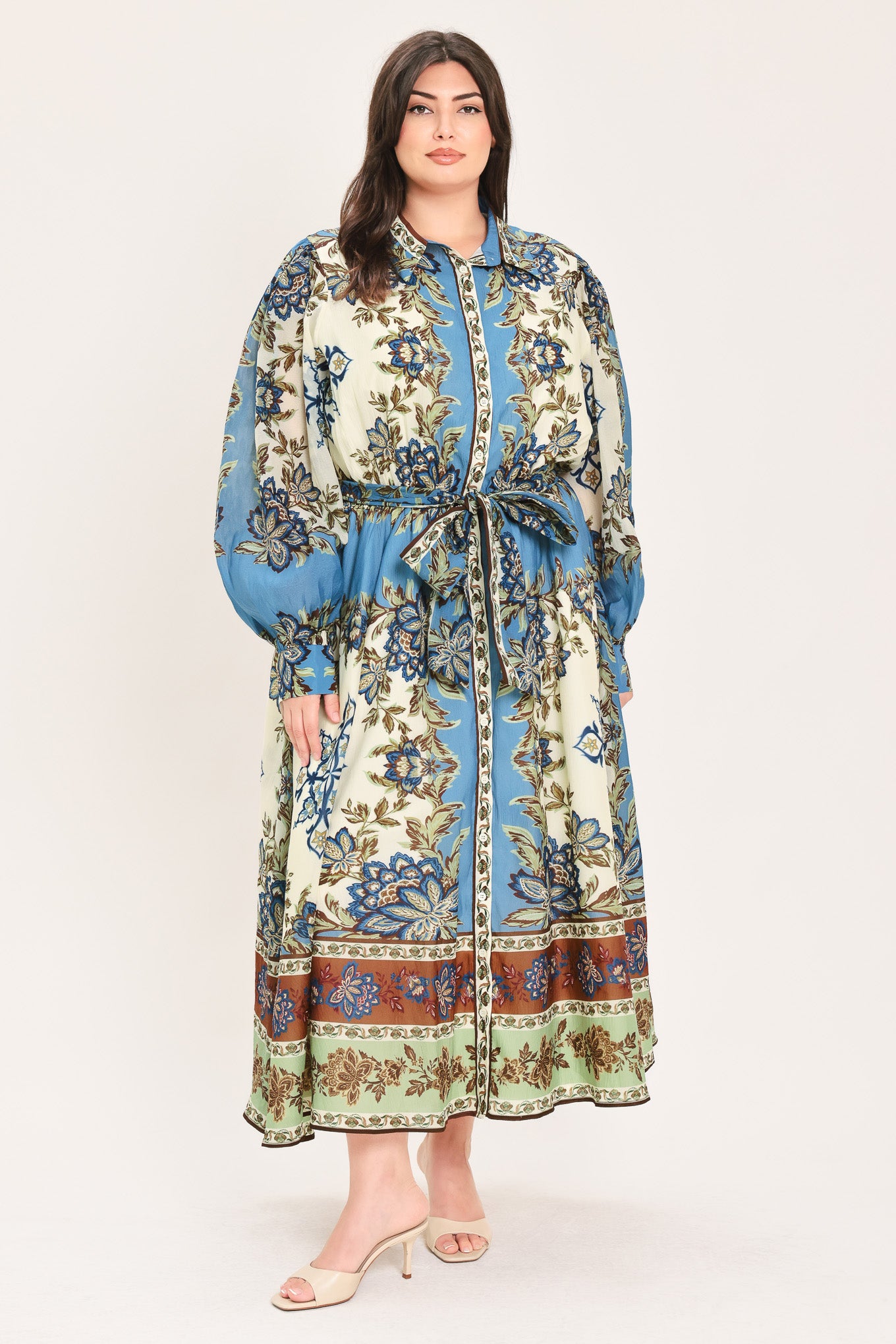 A woman wearing a long-sleeved midi dress with a blue, beige, and brown floral pattern, featuring a tie waist belt | Flying Tomato Curve