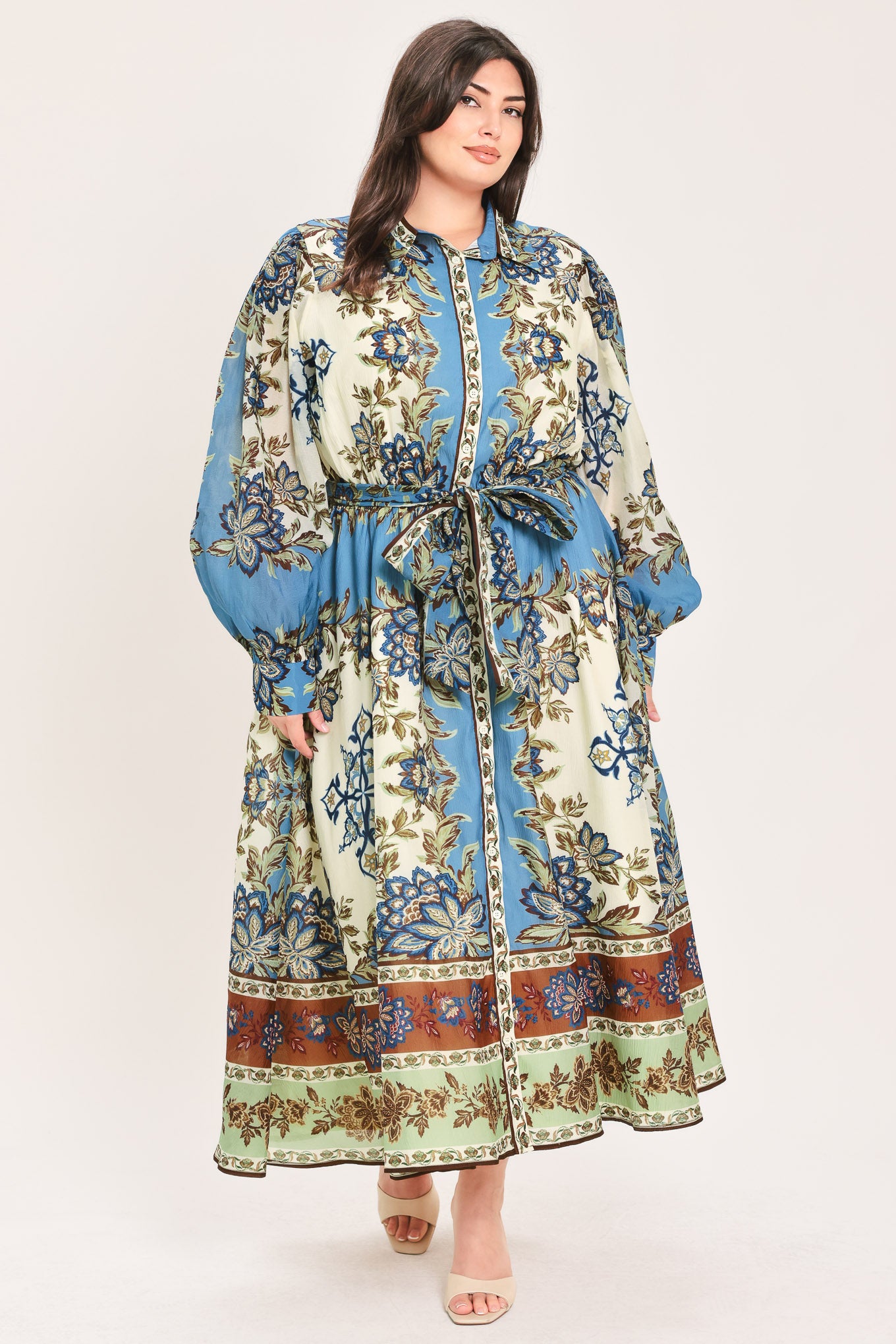 A woman wearing a long-sleeved midi dress with a blue, beige, and brown floral pattern, featuring a tie waist belt | Flying Tomato Curve