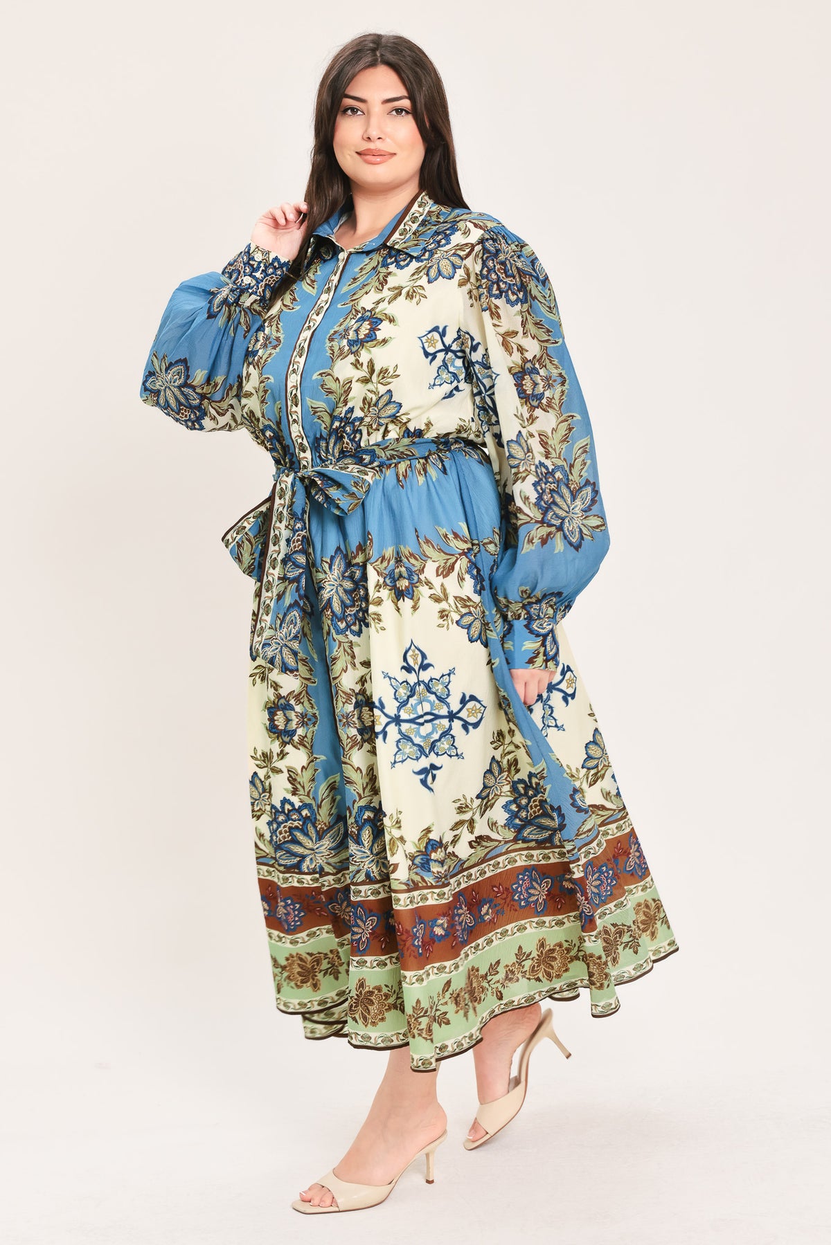 A woman wearing a long-sleeved midi dress with a blue, beige, and brown floral pattern, featuring a tie waist belt | Flying Tomato Curve
