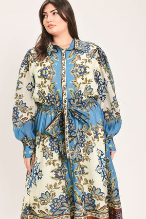 A woman wearing a long-sleeved midi dress with a blue, beige, and brown floral pattern, featuring a tie waist belt | Flying Tomato Curve