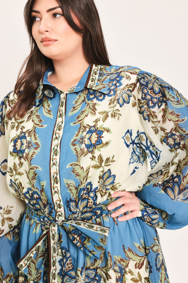 A woman wearing a long-sleeved midi dress with a blue, beige, and brown floral pattern, featuring a tie waist belt | Flying Tomato Curve