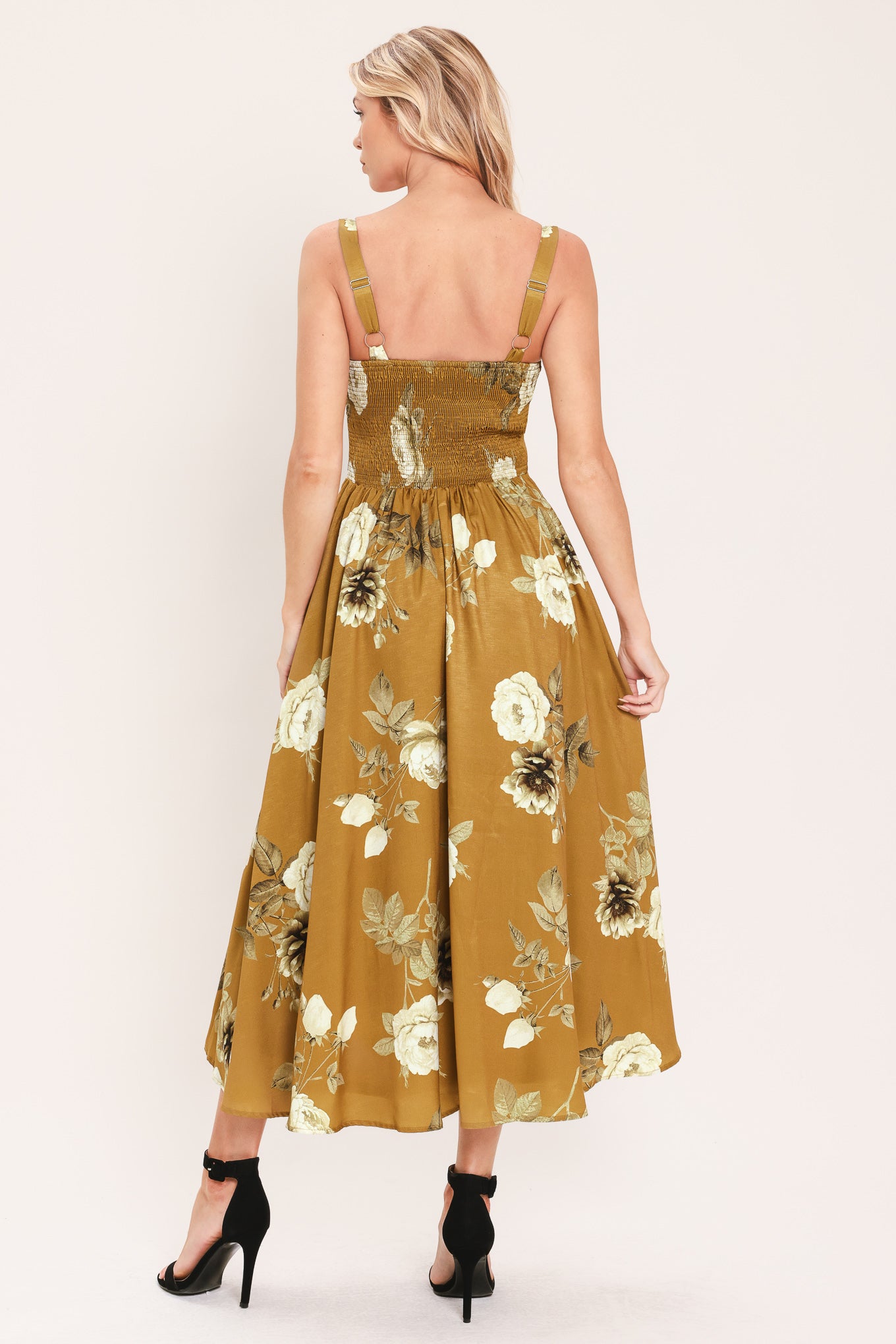 A woman modeling a sleeveless midi dress with a floral print in mustard yellow, cream, and olive green | Flying Tomato
