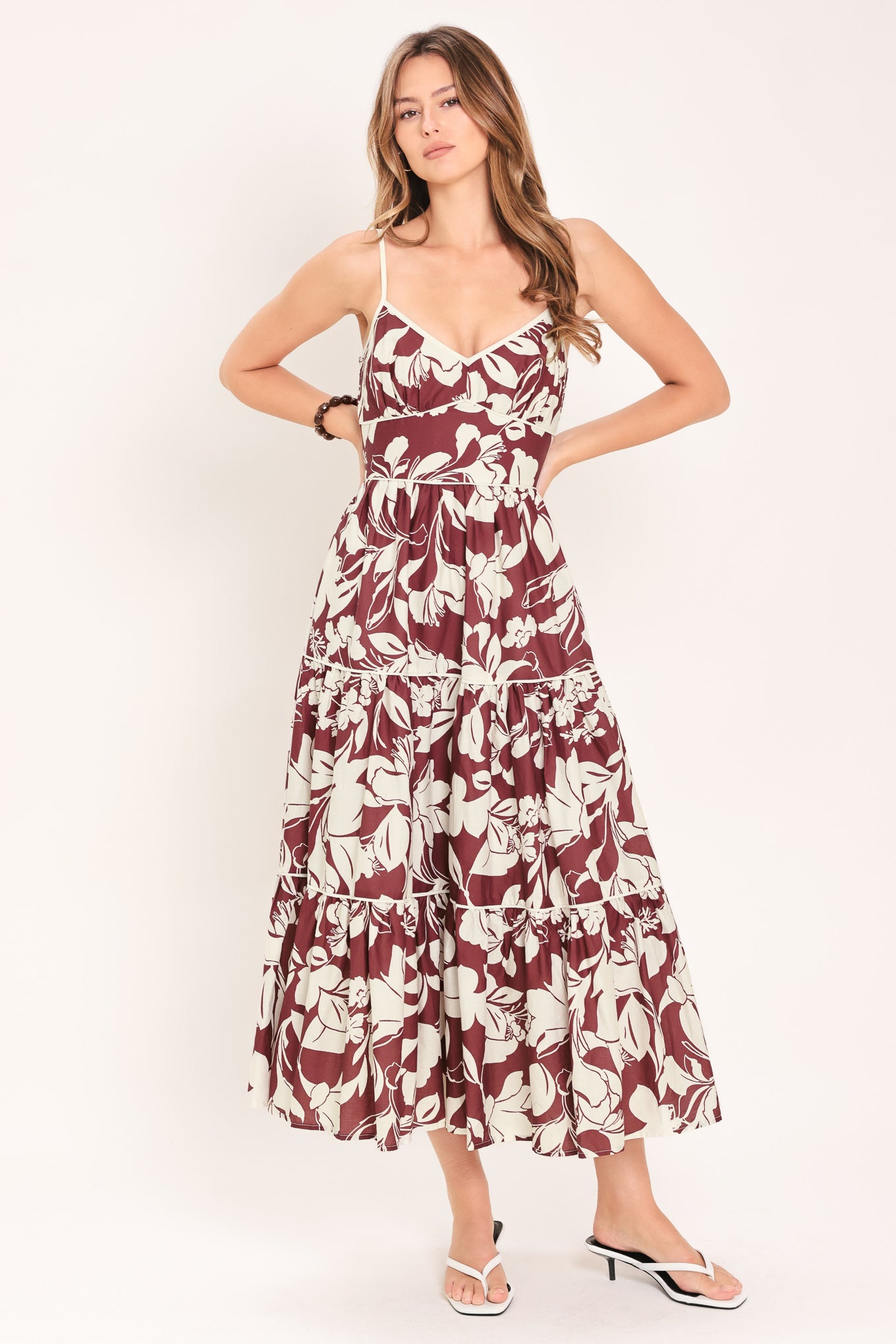 Woman wearing a floral maroon midi dress featuring cami top, waist yoke, tier skirt and smocked back bodice | Flying Tomato