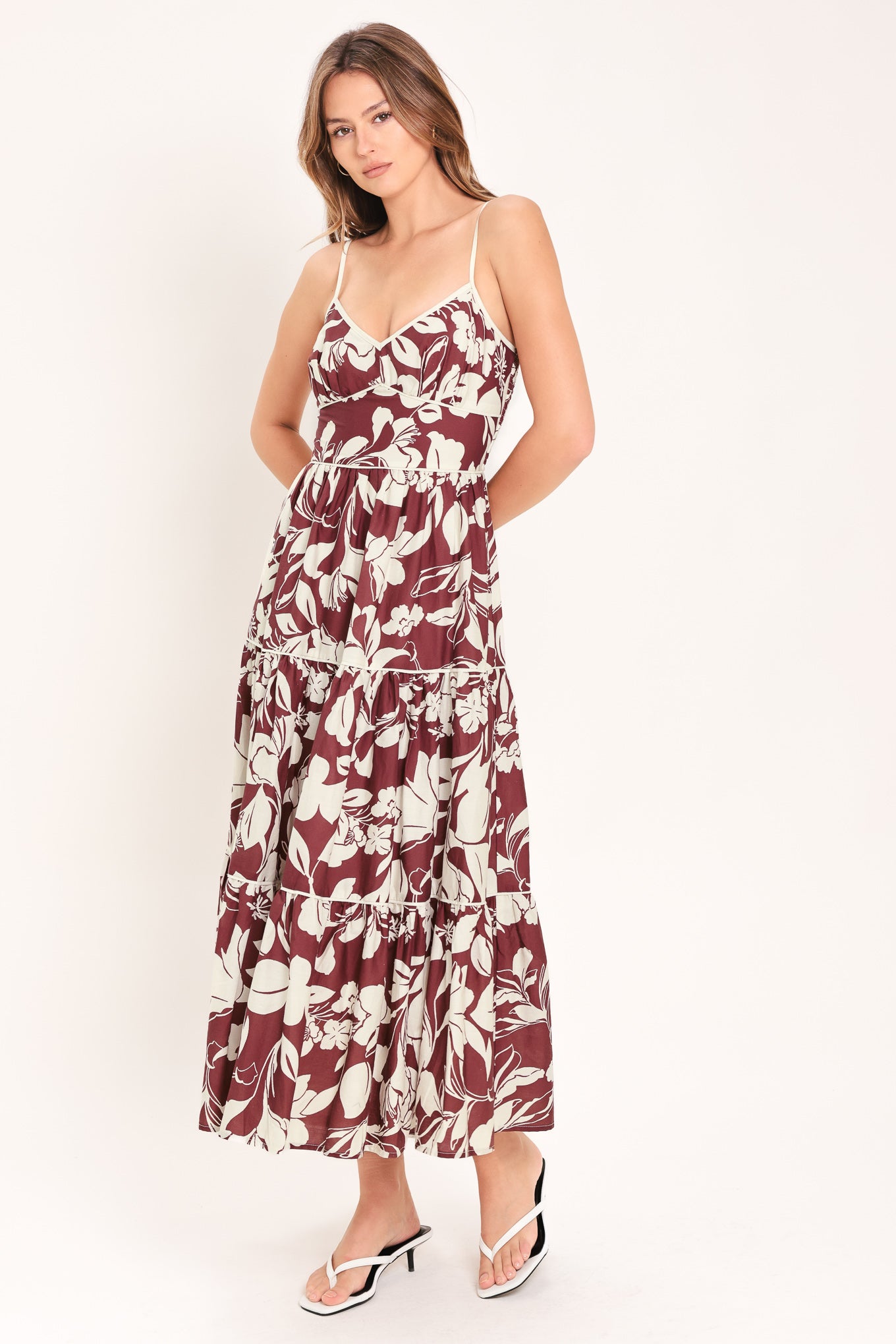 Woman wearing a floral maroon midi dress featuring cami top, waist yoke, tier skirt and smocked back bodice | Flying Tomato