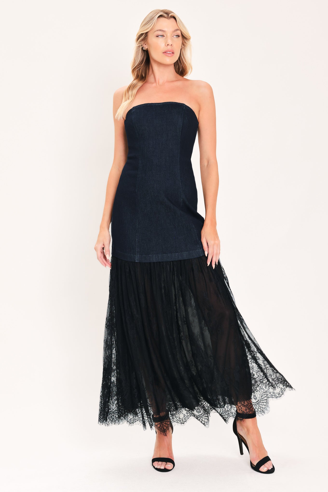 A woman modeling a strapless dark blue maxi dress with a fitted denim-like bodice and a flowing sheer tulle skirt with lace trim | Flying Tomato