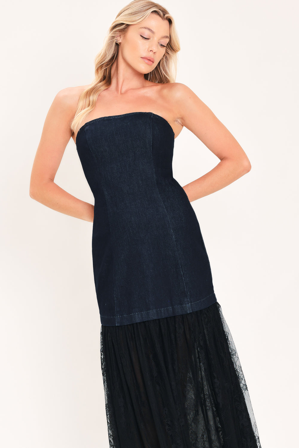 A woman modeling a strapless dark blue maxi dress with a fitted denim-like bodice and a flowing sheer tulle skirt with lace trim | Flying Tomato
