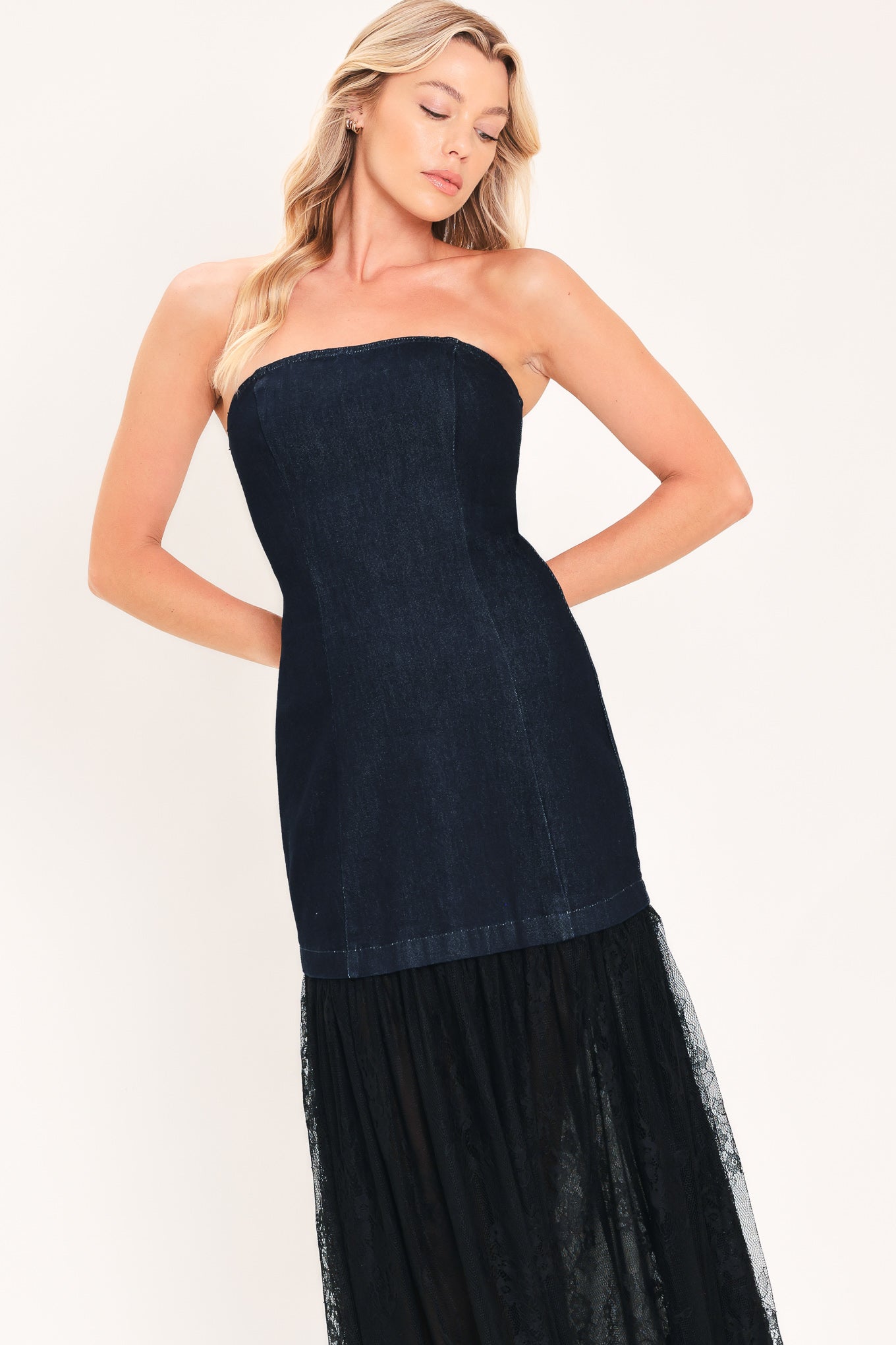 A woman modeling a strapless dark blue maxi dress with a fitted denim-like bodice and a flowing sheer tulle skirt with lace trim | Flying Tomato
