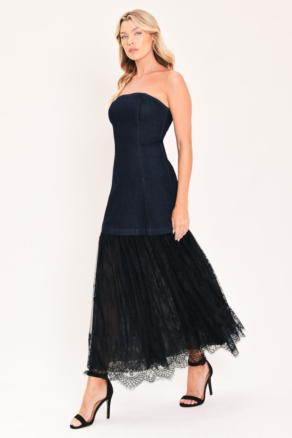 A woman modeling a strapless dark blue maxi dress with a fitted denim-like bodice and a flowing sheer tulle skirt with lace trim | Flying Tomato
