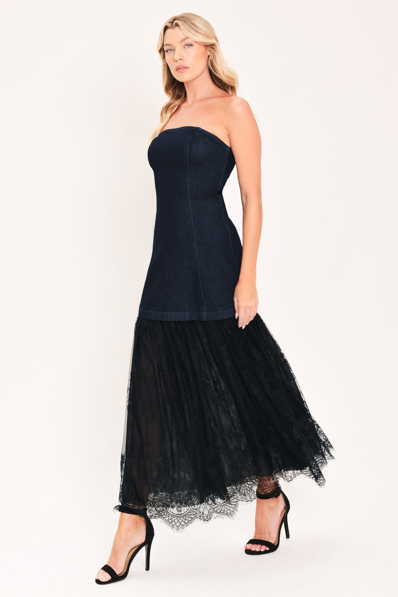 A woman modeling a strapless dark blue maxi dress with a fitted denim-like bodice and a flowing sheer tulle skirt with lace trim | Flying Tomato
