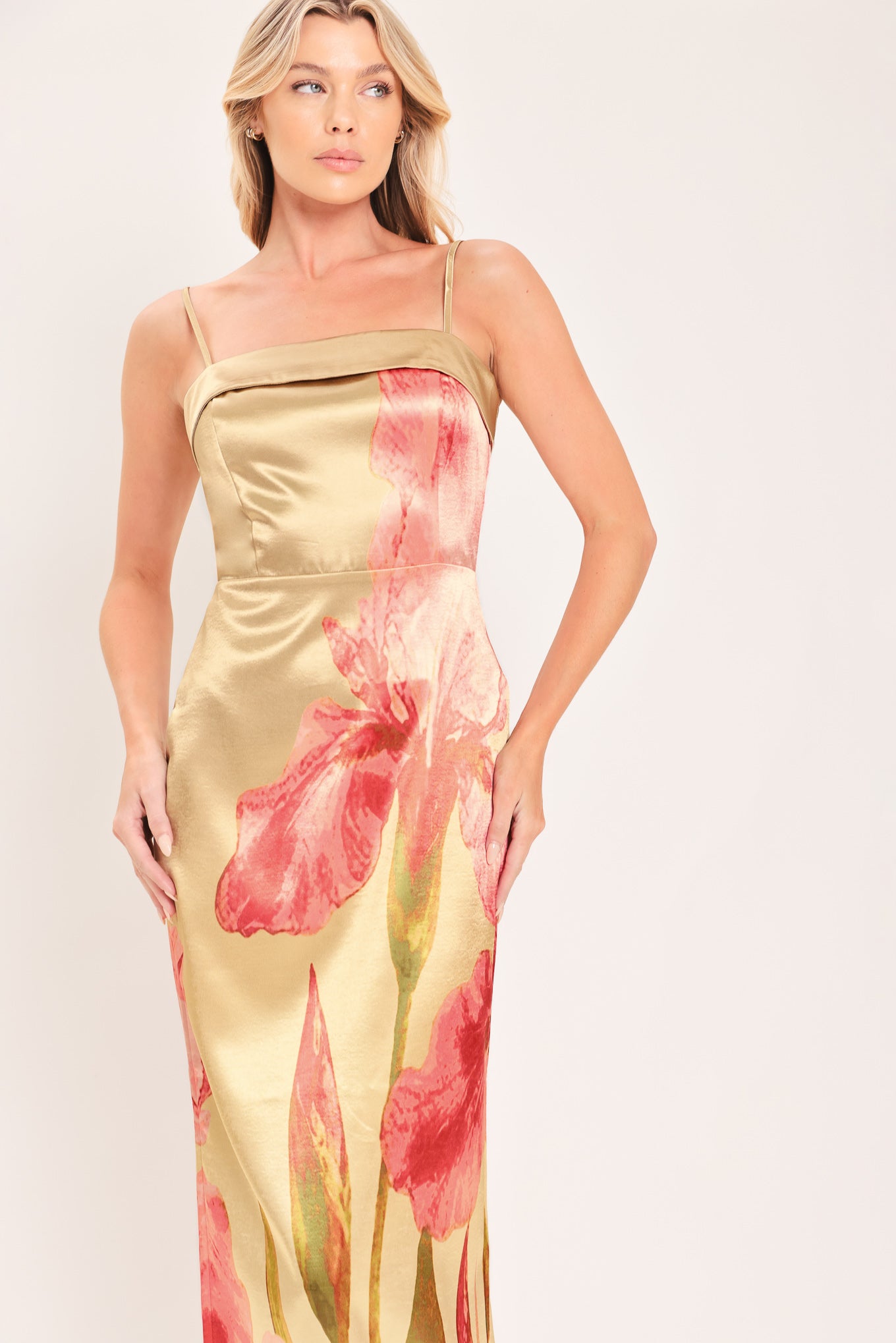 A woman modeling a maxi satin slip dress with a champagne gold base and a large pink floral print | Flying Tomato