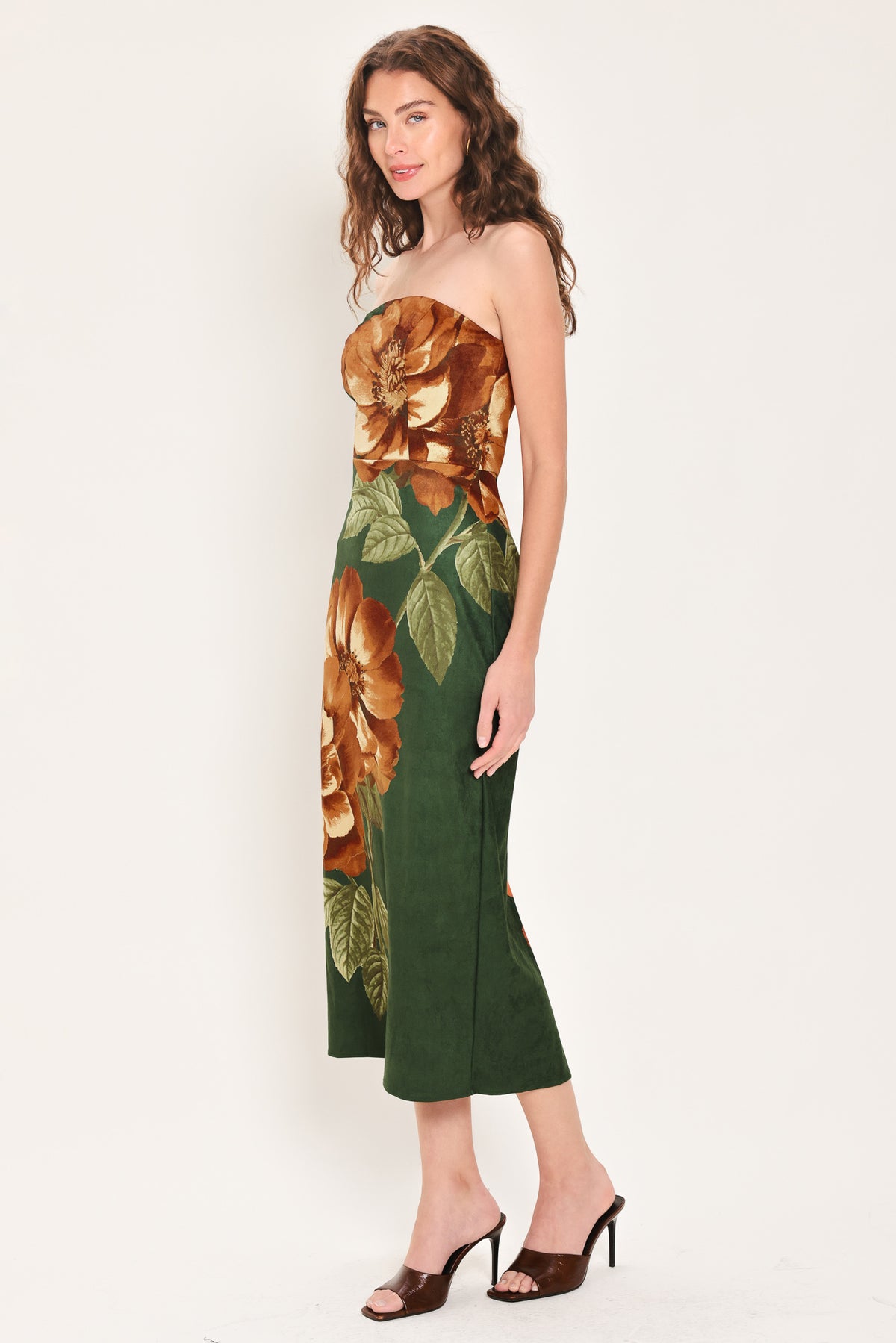 Woman wearing a strapless hunter green suede midi dress with giant rust orange flowers and leaves | Flying Tomato