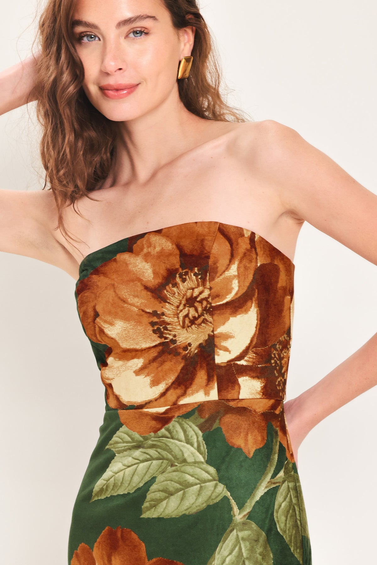 Woman wearing a strapless hunter green suede midi dress with giant rust orange flowers and leaves | Flying Tomato