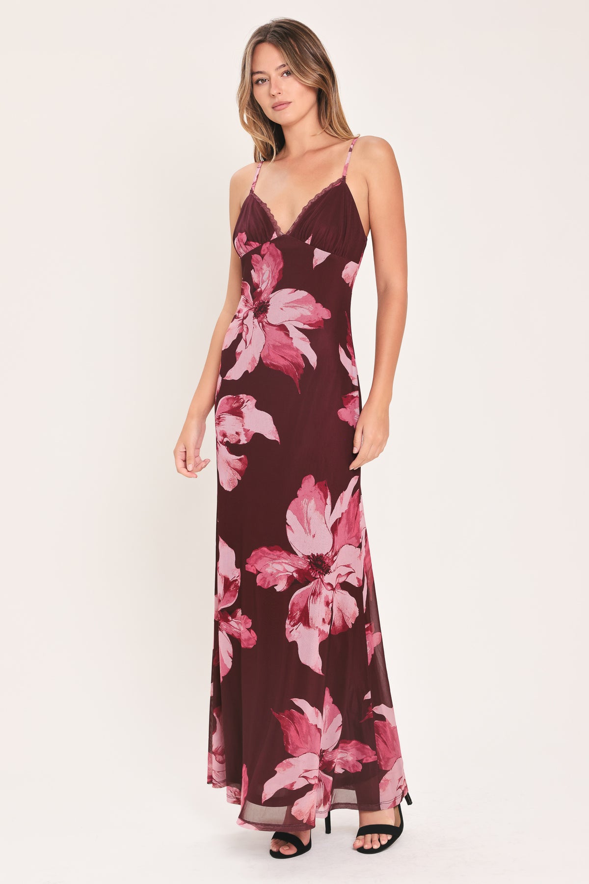 A woman modeling a sleeveless maxi dress with a dark burgundy base and large pink floral print | Flying Tomato