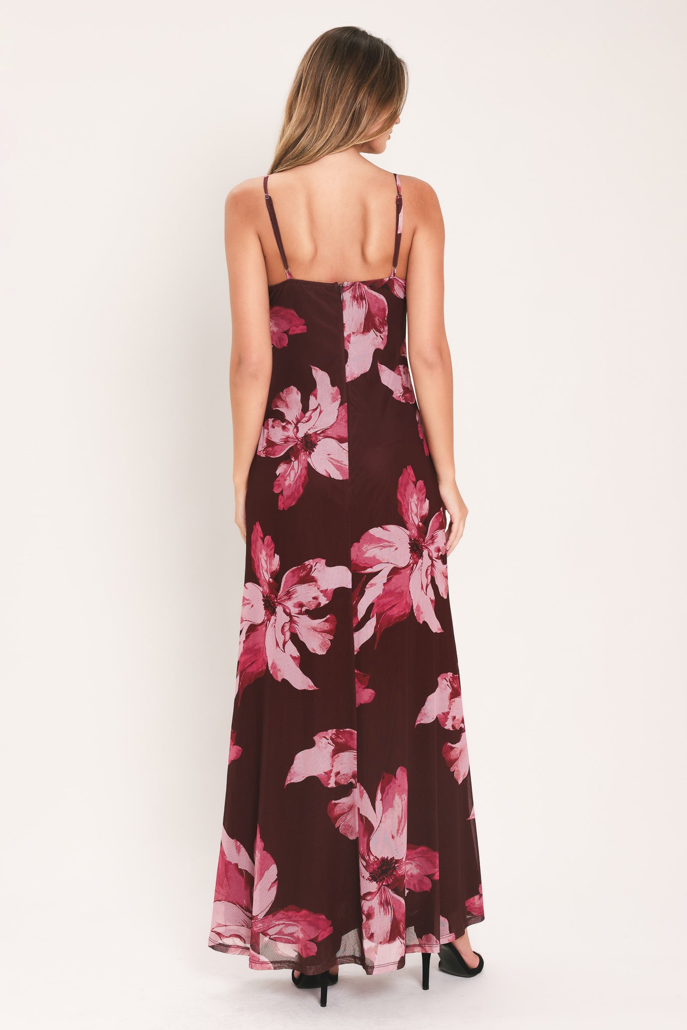 A woman modeling a sleeveless maxi dress with a dark burgundy base and large pink floral print | Flying Tomato