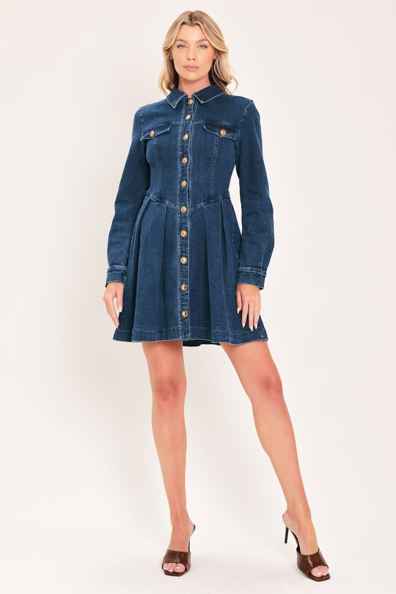 A woman modeling a blue denim long-sleeve shirt dress with gold-tone buttons | Flying Tomato