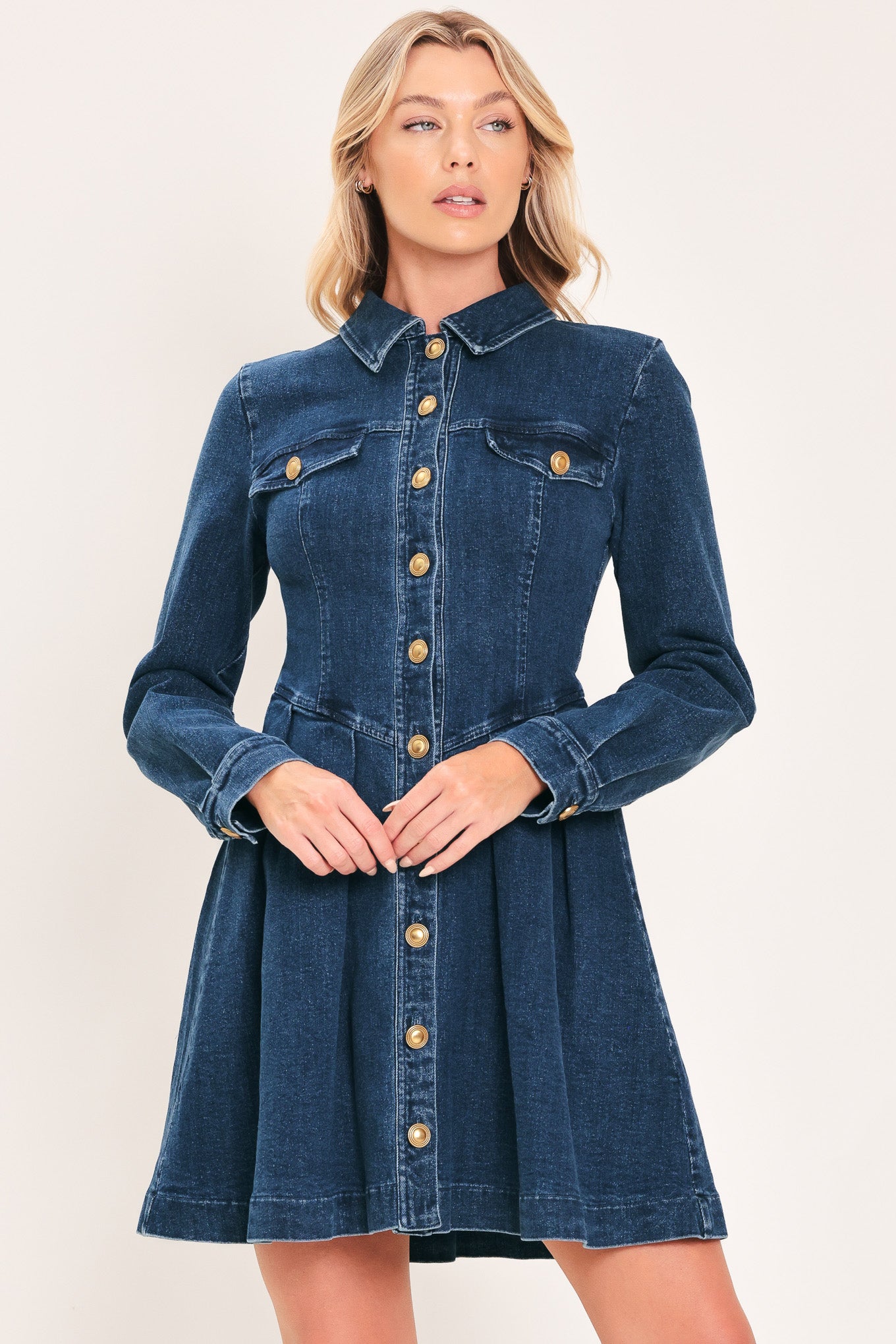 A woman modeling a blue denim long-sleeve shirt dress with gold-tone buttons | Flying Tomato